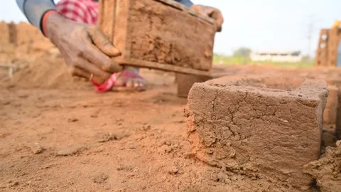A person manually shaping bricks in an open field. Stock Footage 333051106