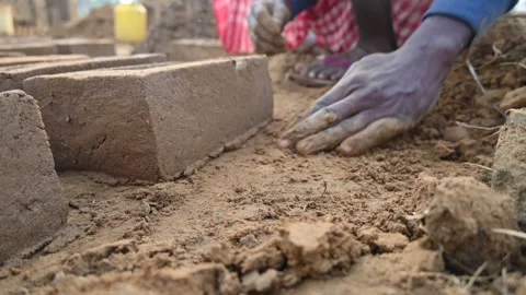 A person manually shaping bricks in an open field. Vídeos de archivo 333051112