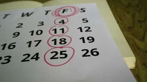 Person marking dates on a paper calendar with a red marker pen for scheduling Stock Footage 341955984