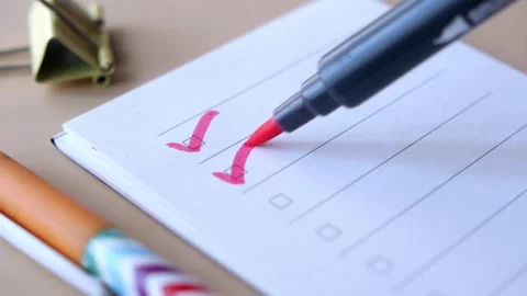 Person marking red check marks on paper list in notepad with felt pen close.. Stock Footage 332627082