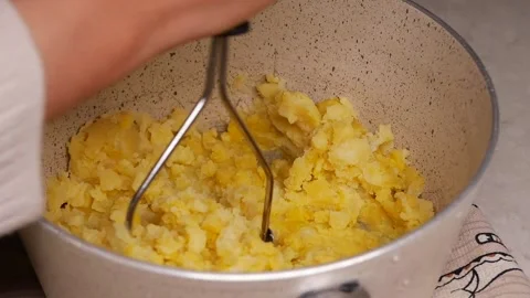 A person mashes potatoes in a pot using a masher. The process is shown clearly Stock Footage 337143703