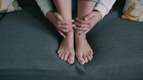 Person massaging legs while sitting down on a mattress indoors Stock Footage 130258363