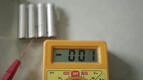 A person measuring the voltage of AAA batteries using a multimeter for checking  Stock Footage 155605437