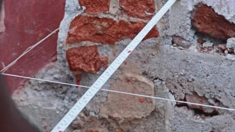Person measuring wall to string line distance through tape at construction Stock Footage 312878416