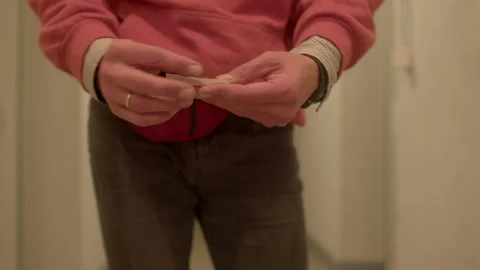 Person methodically rolling tobacco into paper in narrow hallway Stock Footage 322924213