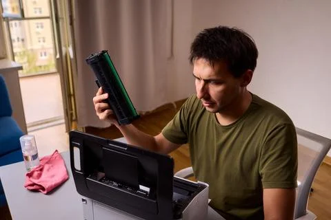 A person meticulously assembling a printer within a brightly lit and organized Stock Photos