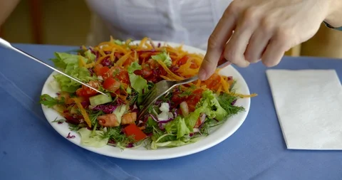 Person mixes salad elements with silver knife and fork Stock Footage 111277086