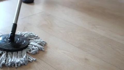 Person mopping light brown laminate floor with microfiber spin mop in home .. Stock Footage 332625913