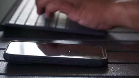 Person multitasking with keyboard and smartphone. Stock Footage 336653550