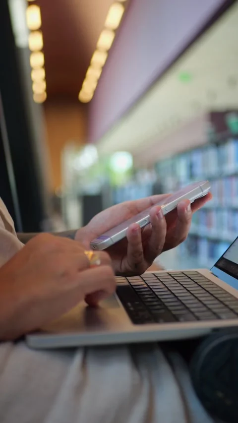 Person Multitasking with Smartphone And Laptop in Library, Technology and... Video stock 334437372