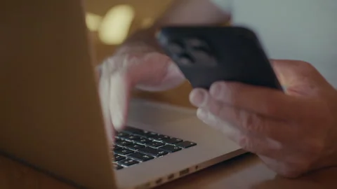 Person multitasking using a smartphone and laptop Stock Footage 346414209