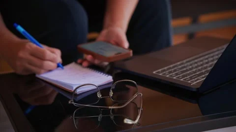 Person multitasks using phone, laptop, and notebook Stock-Footage 333511897