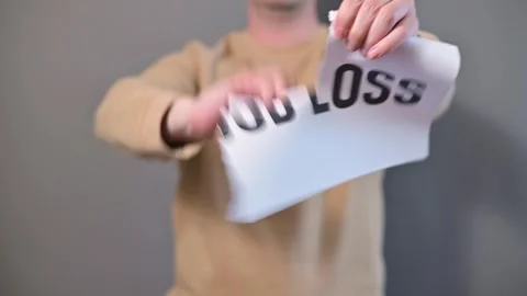 A person, with a neutral expression, holds a sign that reads job loss in a plain Stock-Footage 338299764