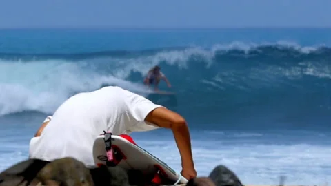 Person observing surfer riding wave in Costa Rica Stock Footage 336875081