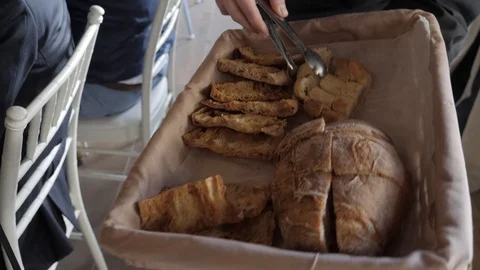 Person offering homemade breads to diners at a family gathering Stockbeeldmateriaal 108839012