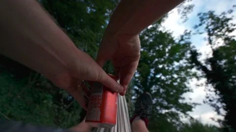 A person opening a beer while swinging in a hammock in woodland Video stock 161347566