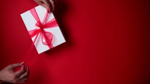 Person opening gift box with red ribbon. Top view of hands opening Christmas Stock Footage 201976686