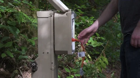 Person opening a power hookup box, and removing a power cord at a campsite. Stock Footage 80550961