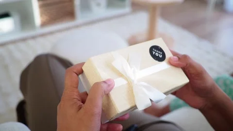 Person opening small white gift box with ribbon and thank you sticker in do.. 스톡 동영상 332117530