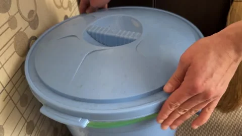 A person opens and closes a round blue plastic trash bin with a snap lid Stock Footage 335075315