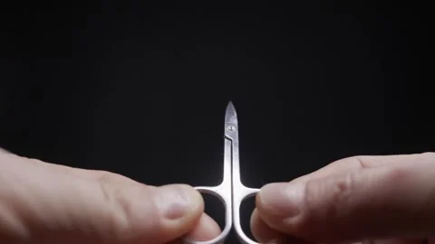 Person Opens and Closes Small Manicure Scissors Against a Black Background Stock Footage 328659339