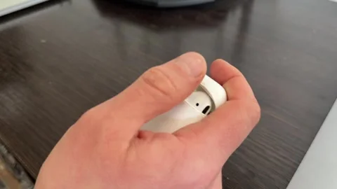 A person opens and closes a small plastic earbud case using one hand Stock Footage 335074493