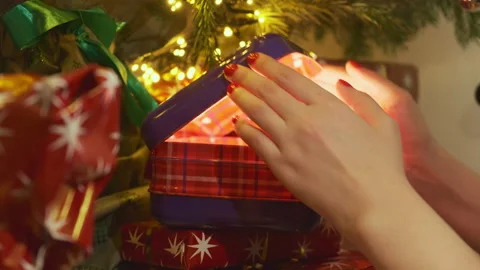 Person opens illuminated present box under Christmas tree Stock Footage 215090390