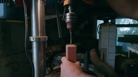 Person operates a drill press machine to bore a hole in wooden workpiece Video stock 336278424