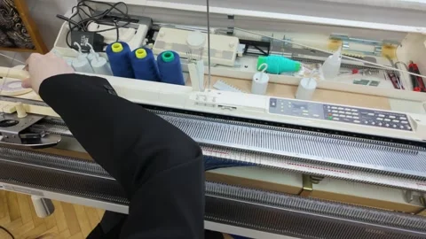 Person operating a manual knitting machine for creating fabric patterns in .. Stock Footage 339779000