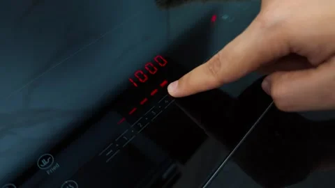 Person operating a modern induction cooktop, adjusting power levels on the touch Stock Footage 345515805