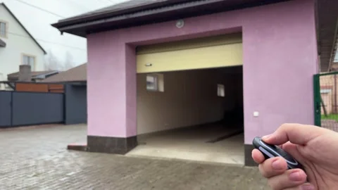 Person is operating a remote control closing a garage door or gate for a car. Stock Footage 346721801