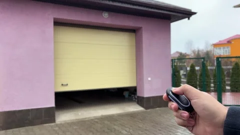 Person is operating a remote control opening a garage door or gate for a car. Stock Footage 346721781