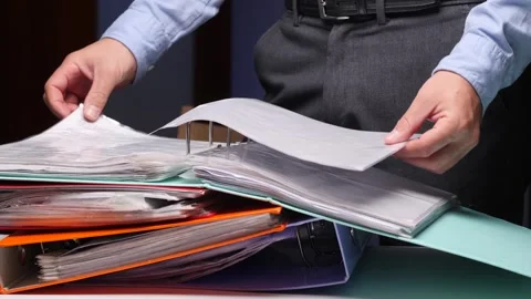 Person organizing documents in office binder, searching paperwork Stock Footage 322913443
