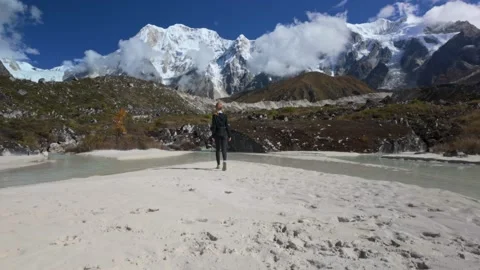 Person overlooking an immense mountain and glacial river. Remote trekking view Stock Footage 323163843