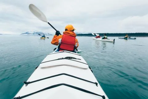 A person paddling in a double sea kayak on calm water off the coast of Alaska. Stock Photos