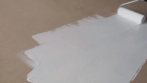 Person Painting Surface Using a Roller With White Paint on a Brown Panel Stock Footage 309095484