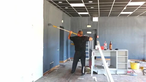 Person paints wall in empty room during renovation process in a commercial space Stock Footage 325526545