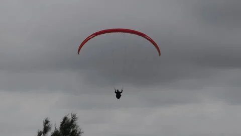 Person paragliding high in cloudy sky Видео 342199530