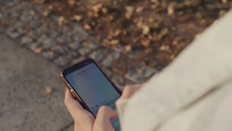 Person in the park is typing a text message.  Human walks  in the park and .. Stock Footage 254657379