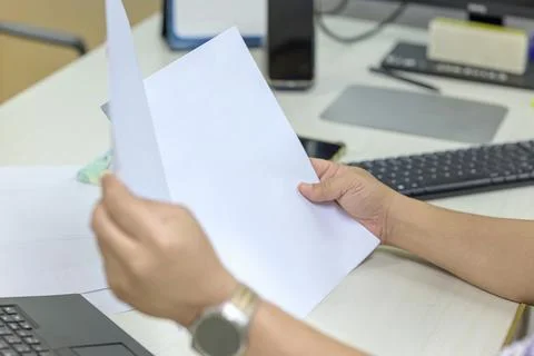 A person in a patterned shirt is reviewing a stack of white papers or a bus.. Stock Photos