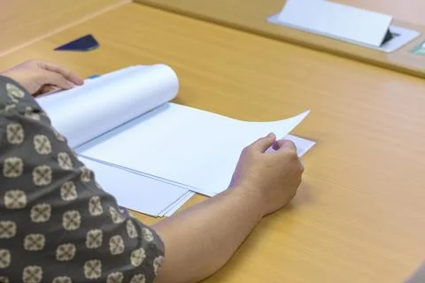 A person in a patterned shirt is reviewing a stack of white papers or a bus.. Stock Photos