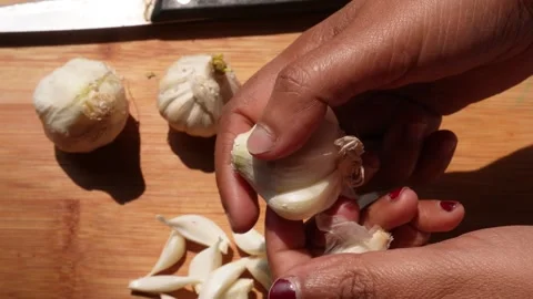 Person peeling cloves from a bulb of garlic Stockbeeldmateriaal 332575673