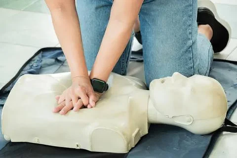 Person performing cpr on a training dummy in a classroom Stock Photos