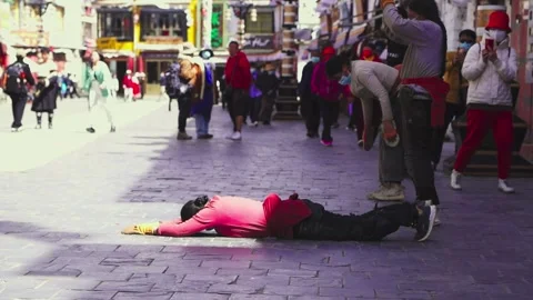 Person performing prostrations on a busy Lhasa pedestrian street Stock Footage 345883254