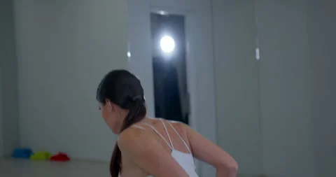 Person performs dumbbell bent over row exercise in gym setting with mirrors and Stock Footage 328895723