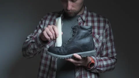 A person performs leather boot maintenance by applying cream to the toe area Stock Footage 334213241