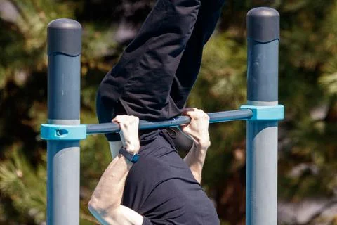 Person performs pull-up on outdoor gym bar Stock Photos