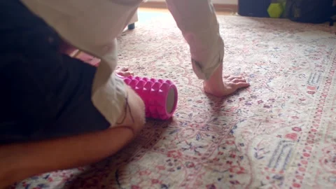Person performs targeted thigh massage with foam roller during warmup Stock Footage 320958764