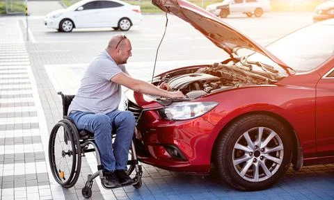 Person with a physical disability check engine his car at parking Stock Photos