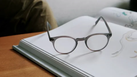Person picking up glasses placed on notebook Stock Footage 130642535